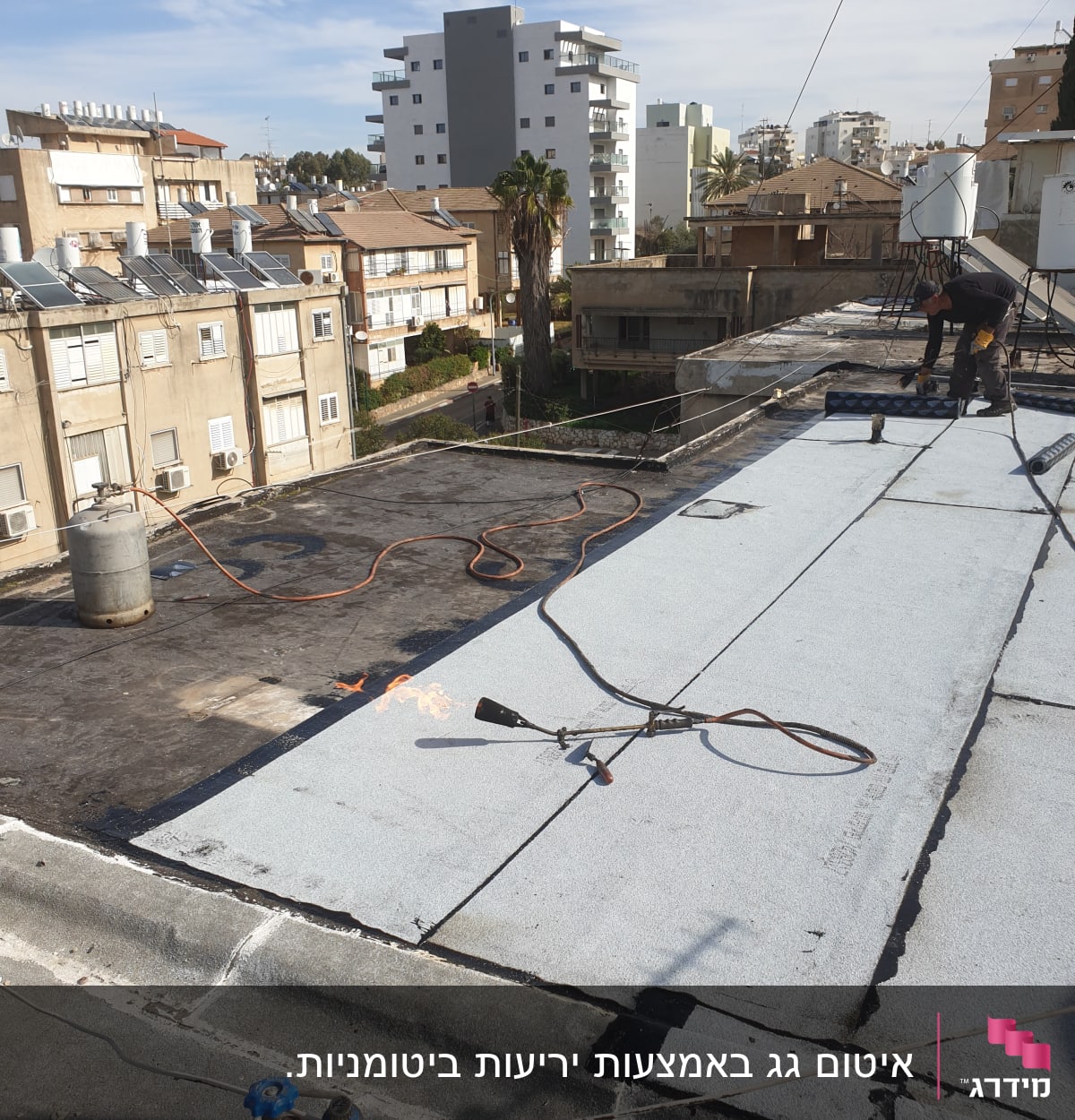 עובד מבצע איטום גג עם יריעות ביטומניות